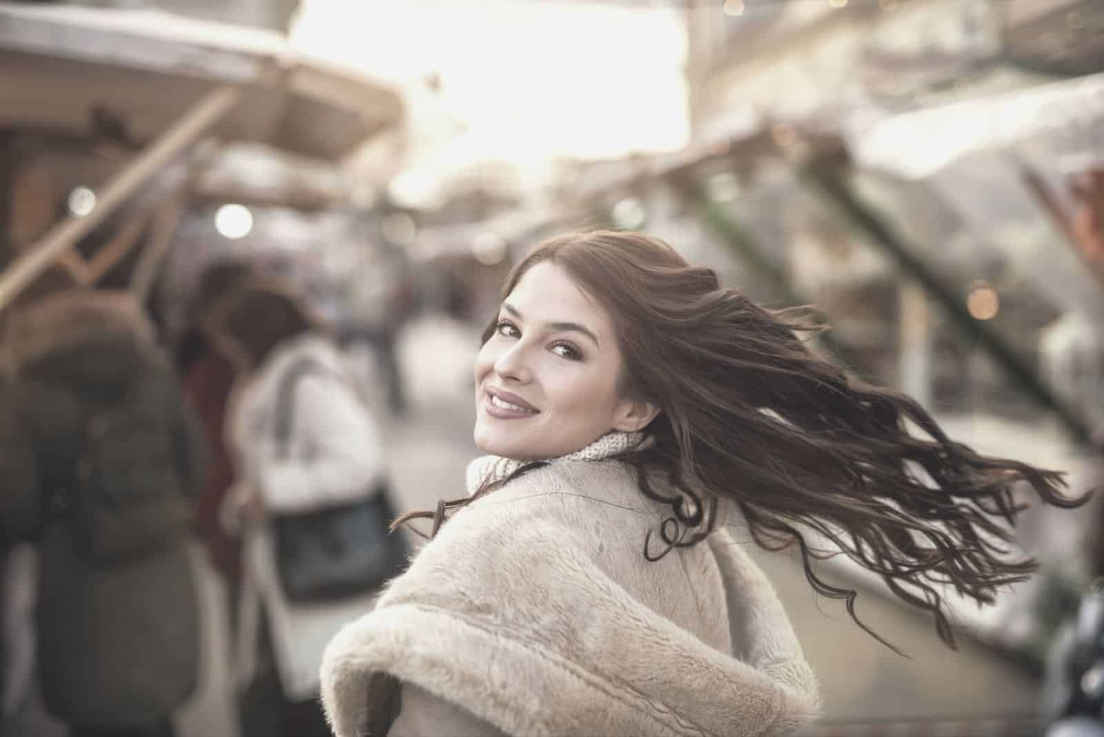 ritratto ravvicinato di una donna affascinante che guarda la macchina fotografica sorridendo mentre cammina nel mercato
