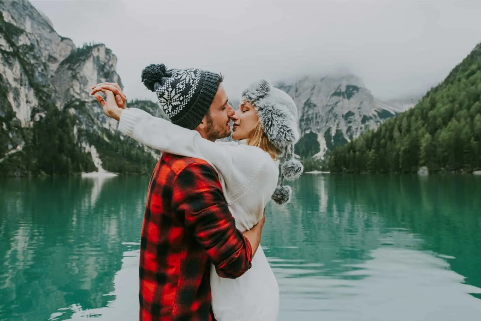 man and woman about to kiss while standing near lake