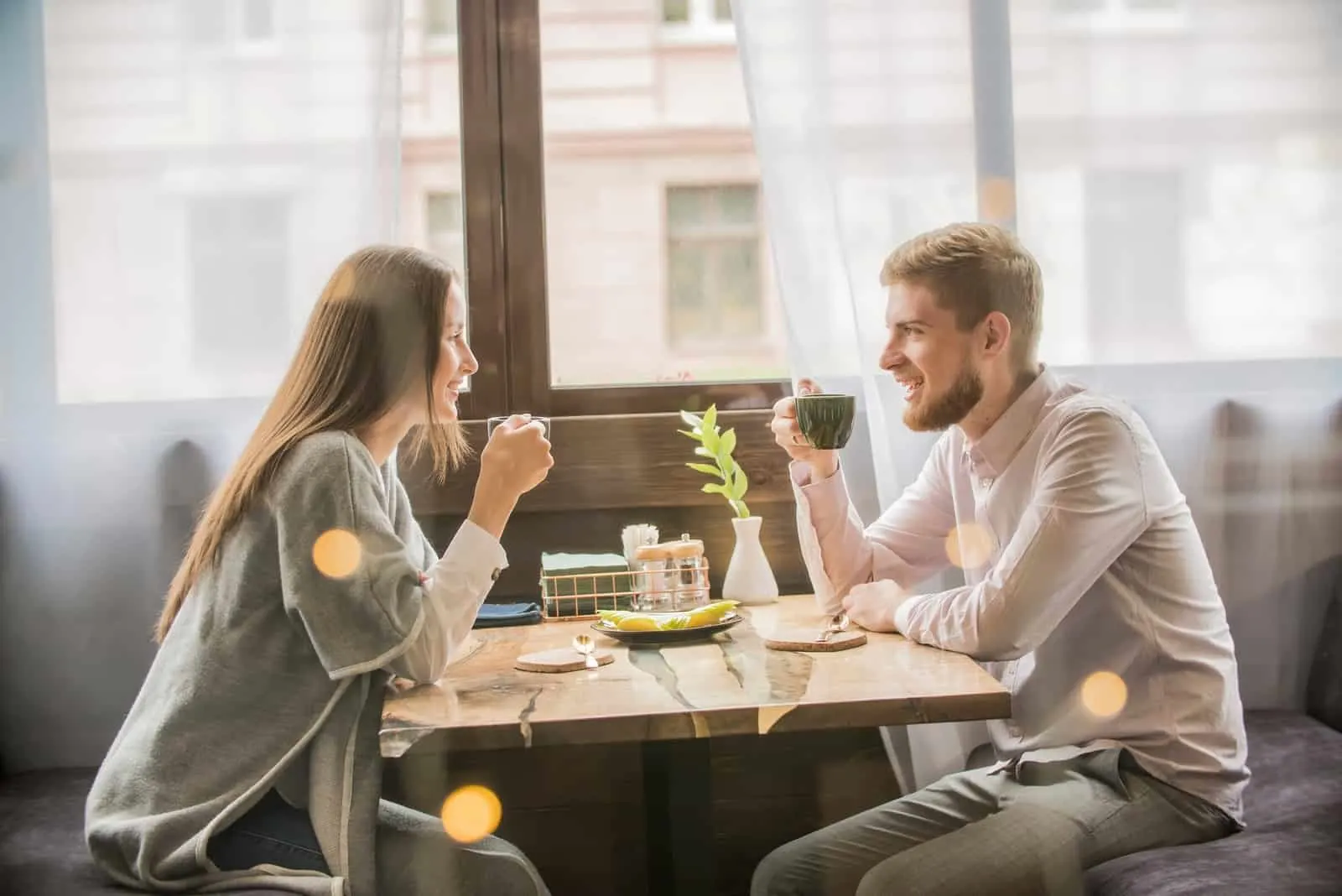 man and woman drinking coffee while sitting in cafe