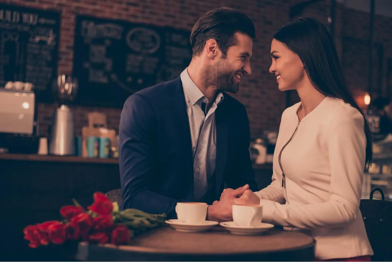 man and woman holding hands while sitting in cafe