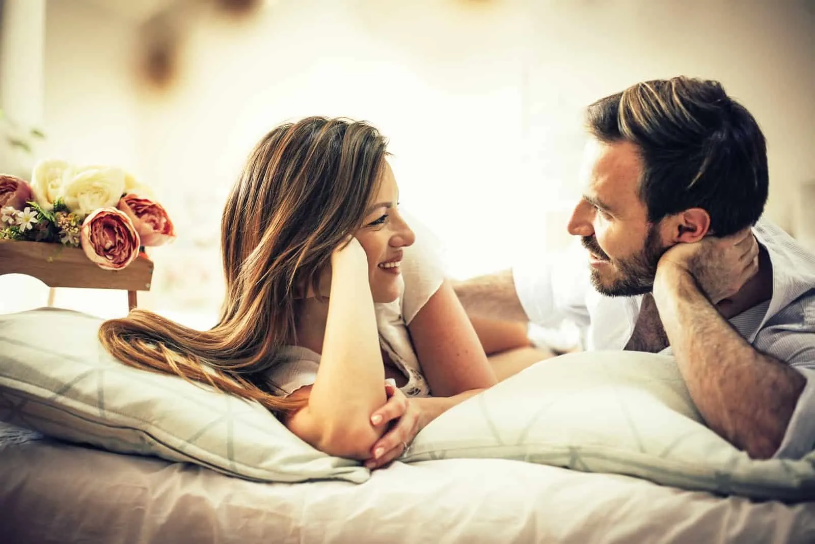 man and woman making eye contact while laying on bed
