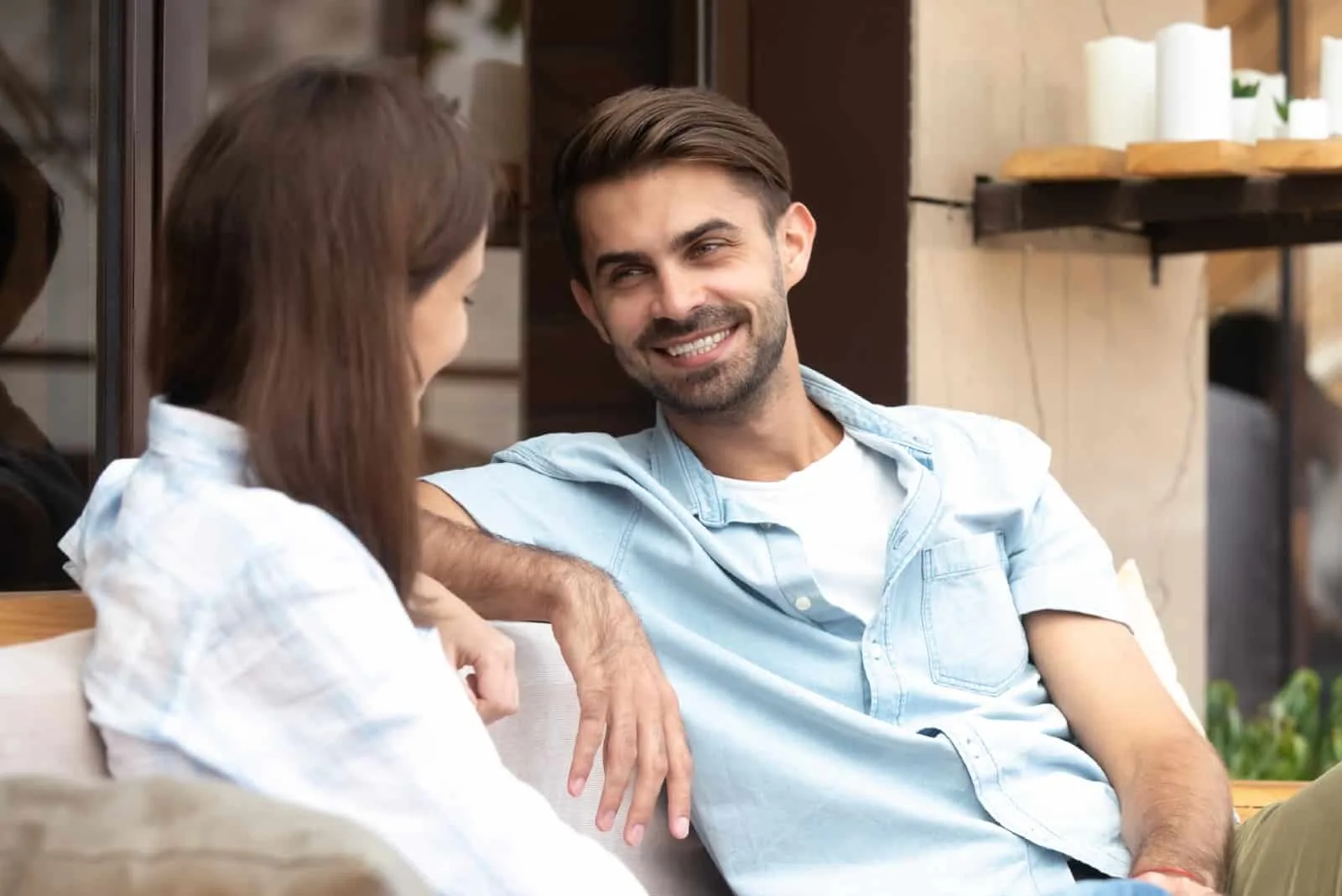 happy man in blue shirt and woman sitting near storefront