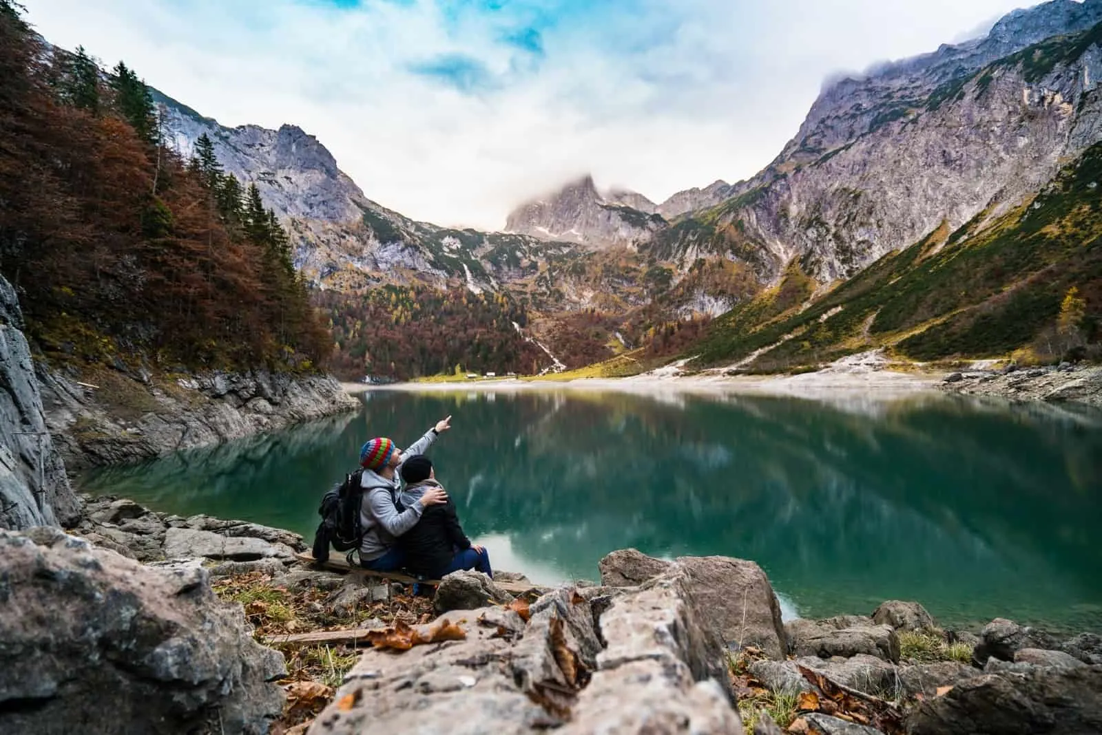 man and woman sitting on rock looking at mountain