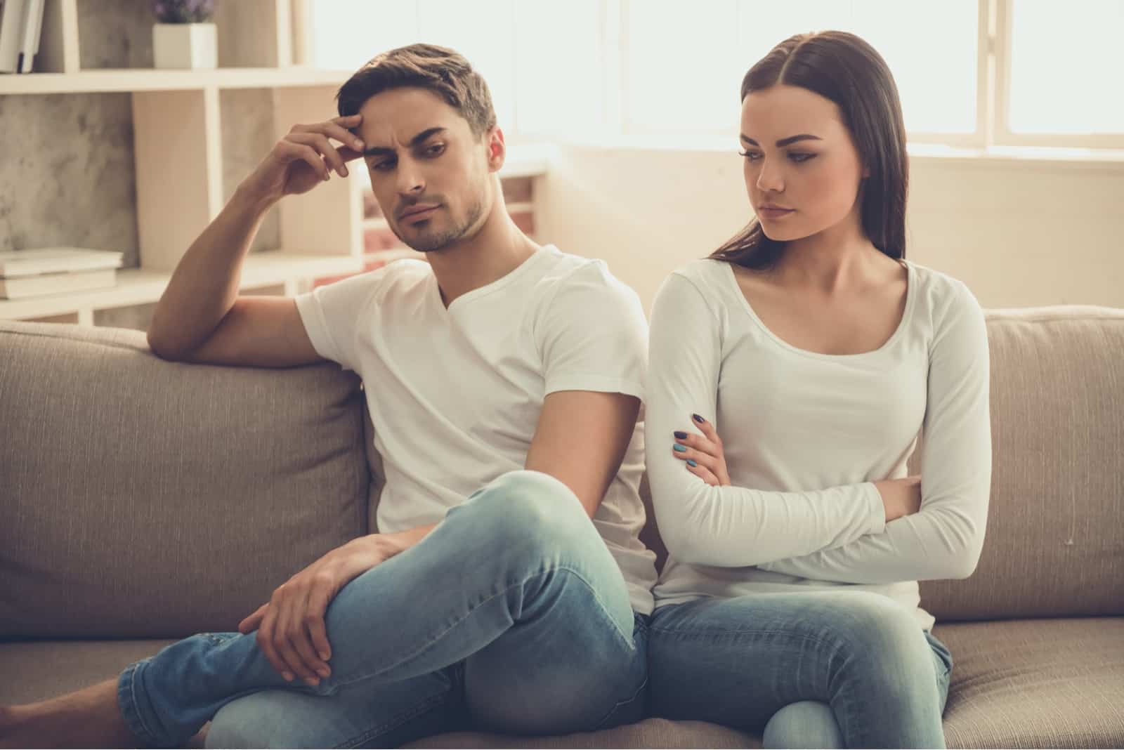 homem zangado de t-shirt branca e mulher sentada no sofá