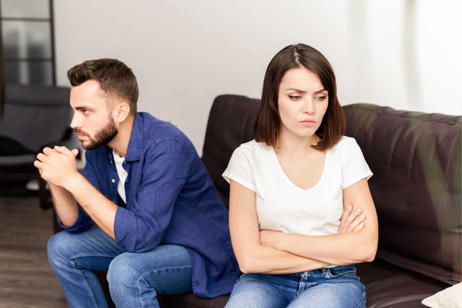 angry woman in white t-shirt sitting on sofa near man