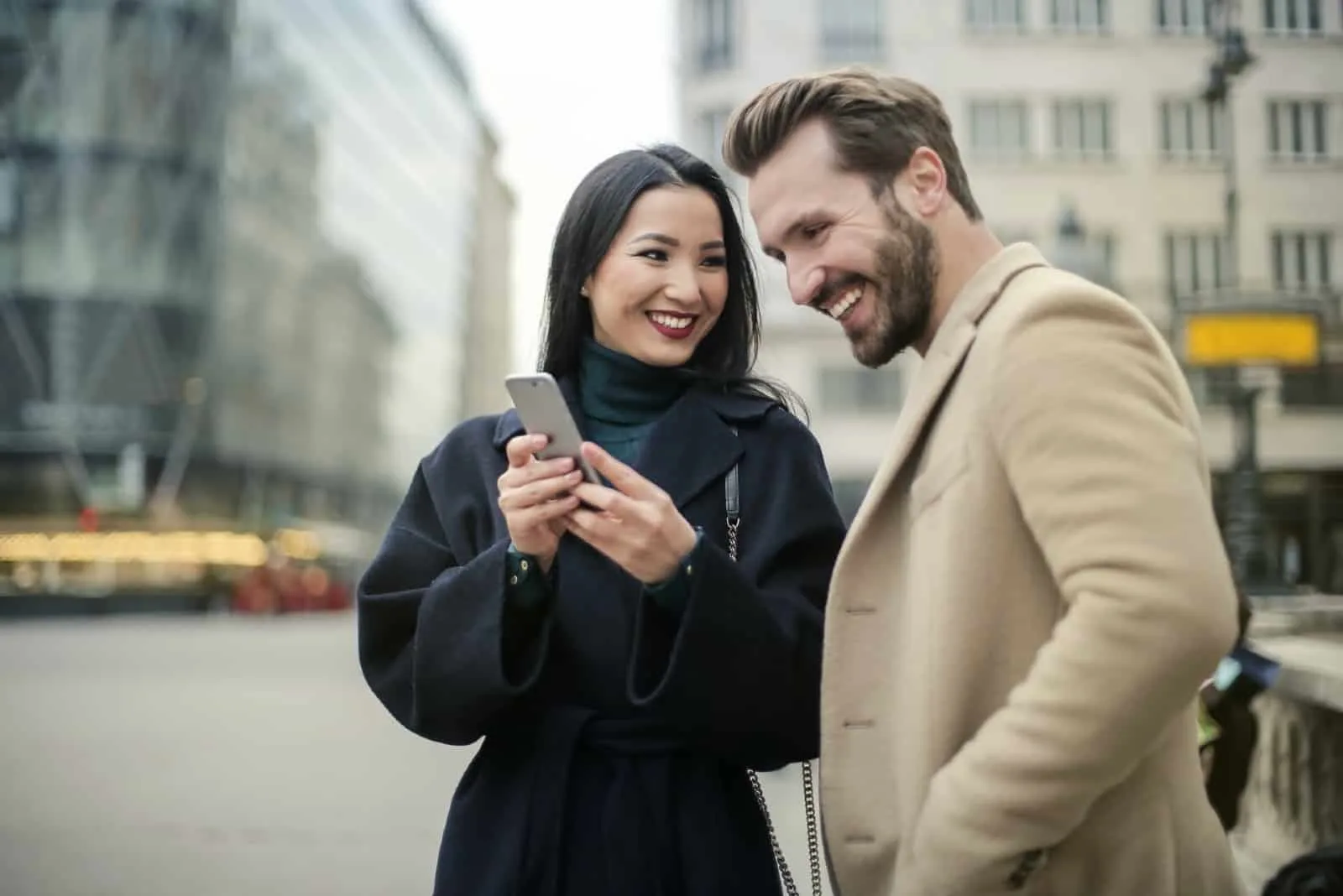man and woman looking at phone while standing on the street