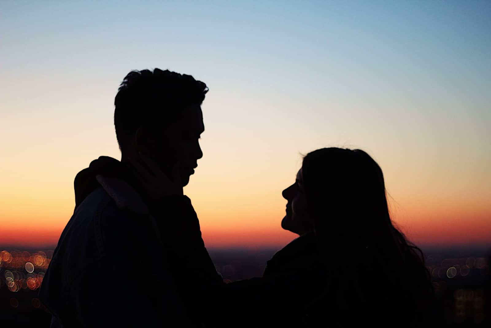 uomo e donna che si guardano negli occhi mentre si trovano all'aperto durante il tramonto