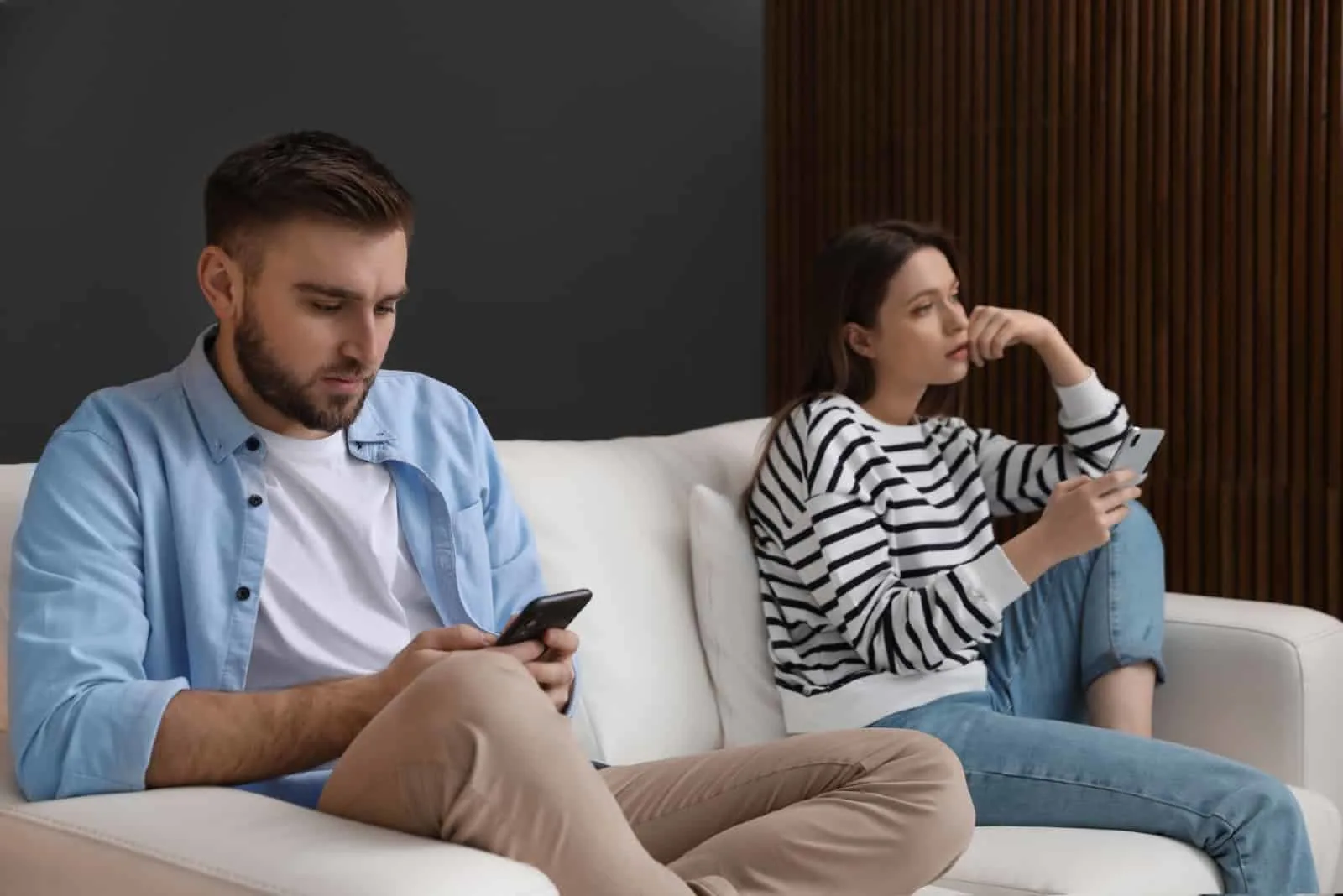 man and woman using smartphones while sitting on sofa