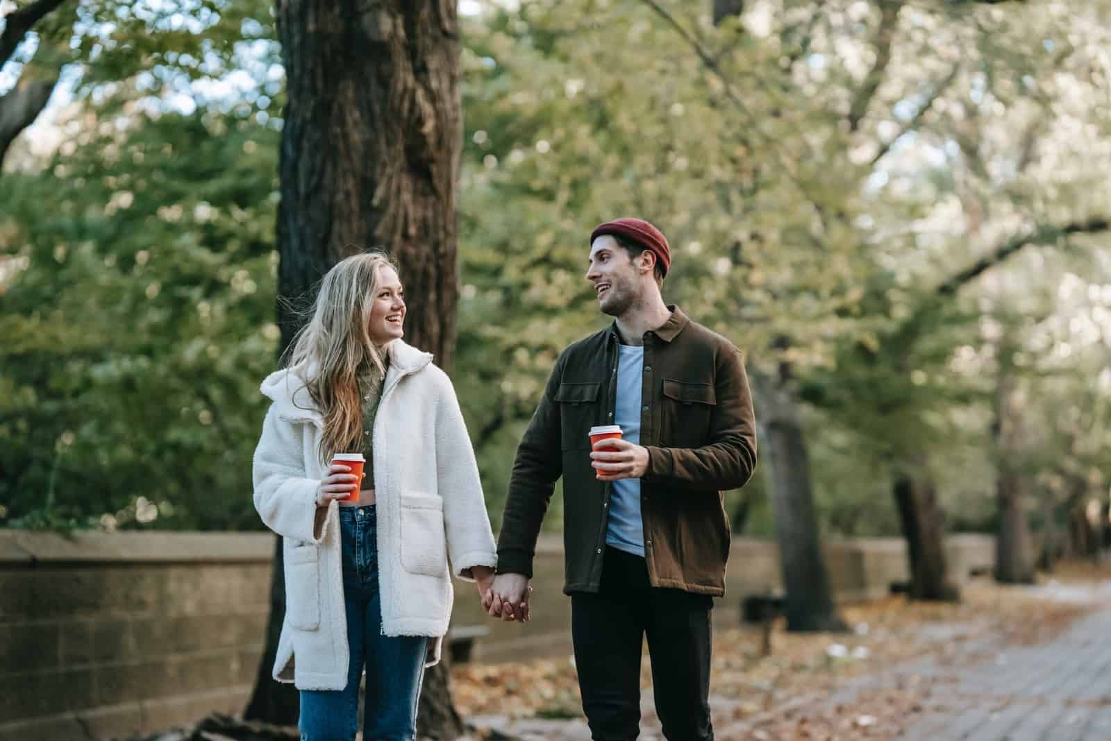 man and woman holding hands while walking down the street