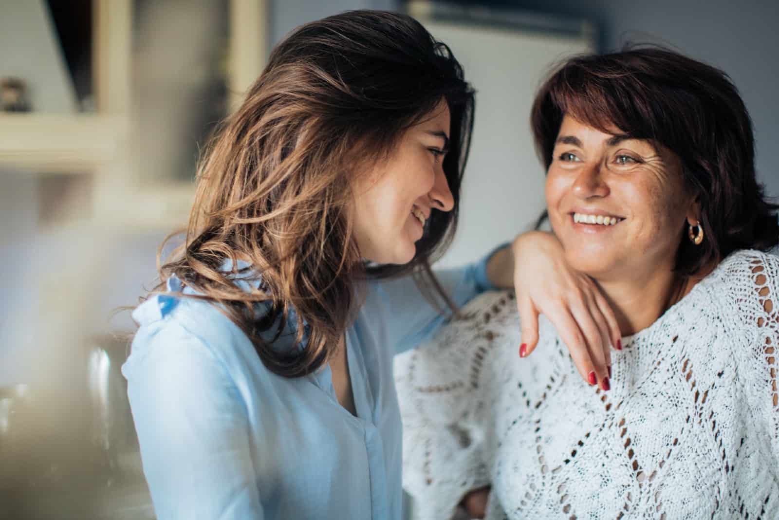 happy daughter looking at mother while standing in the kitchen