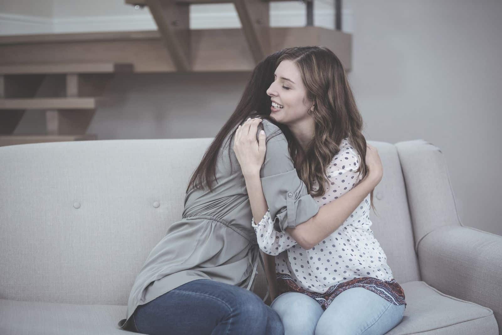 Amiche donne che si abbracciano sedute sul divano del soggiorno