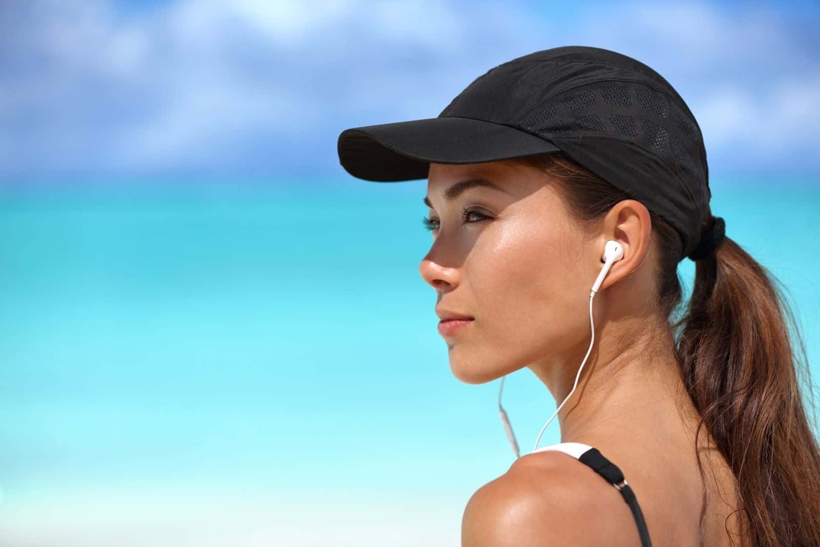 fitness runner ragazza che ascolta la musica con gli auricolari indossando un berretto all'aperto fotografia a fuoco
