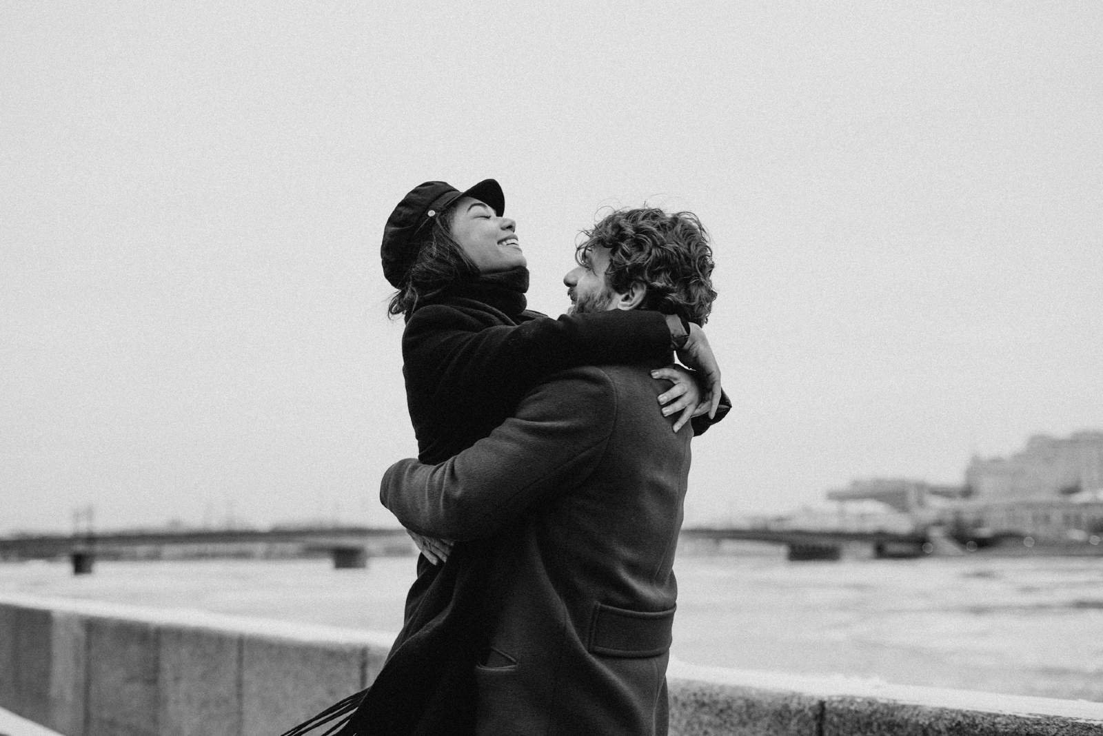 man carrying woman while standing near water