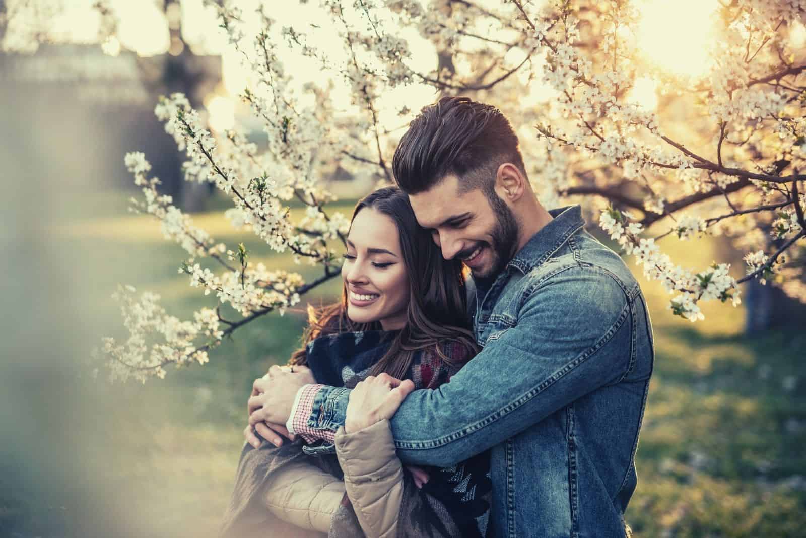 uomo che abbraccia dolcemente la sua ragazza nel giardino fiorito