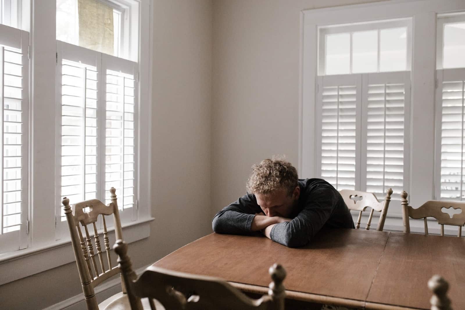 sad man in black top leaning on table