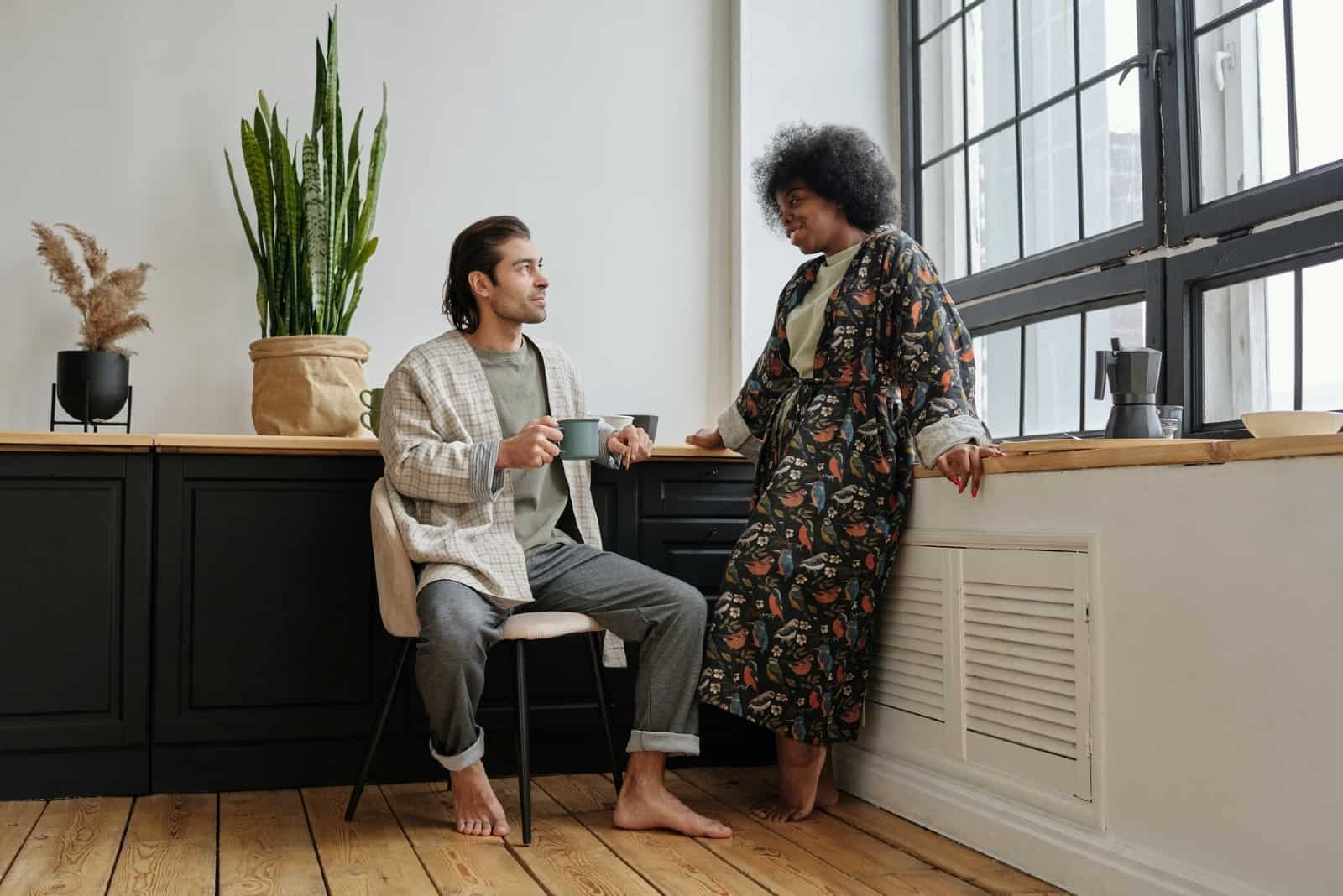 man with mug looking at woman while sitting on chair