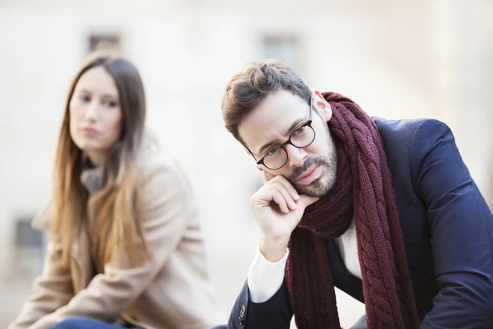 pensive man with eyeglasses sitting near woman outdoor