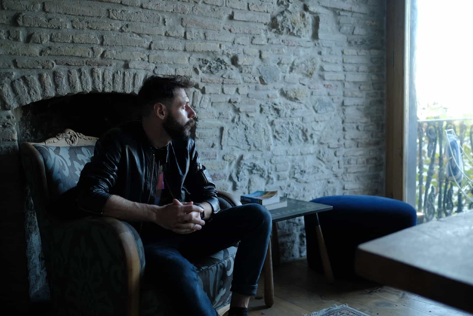 pensive man with beard sitting on armchair