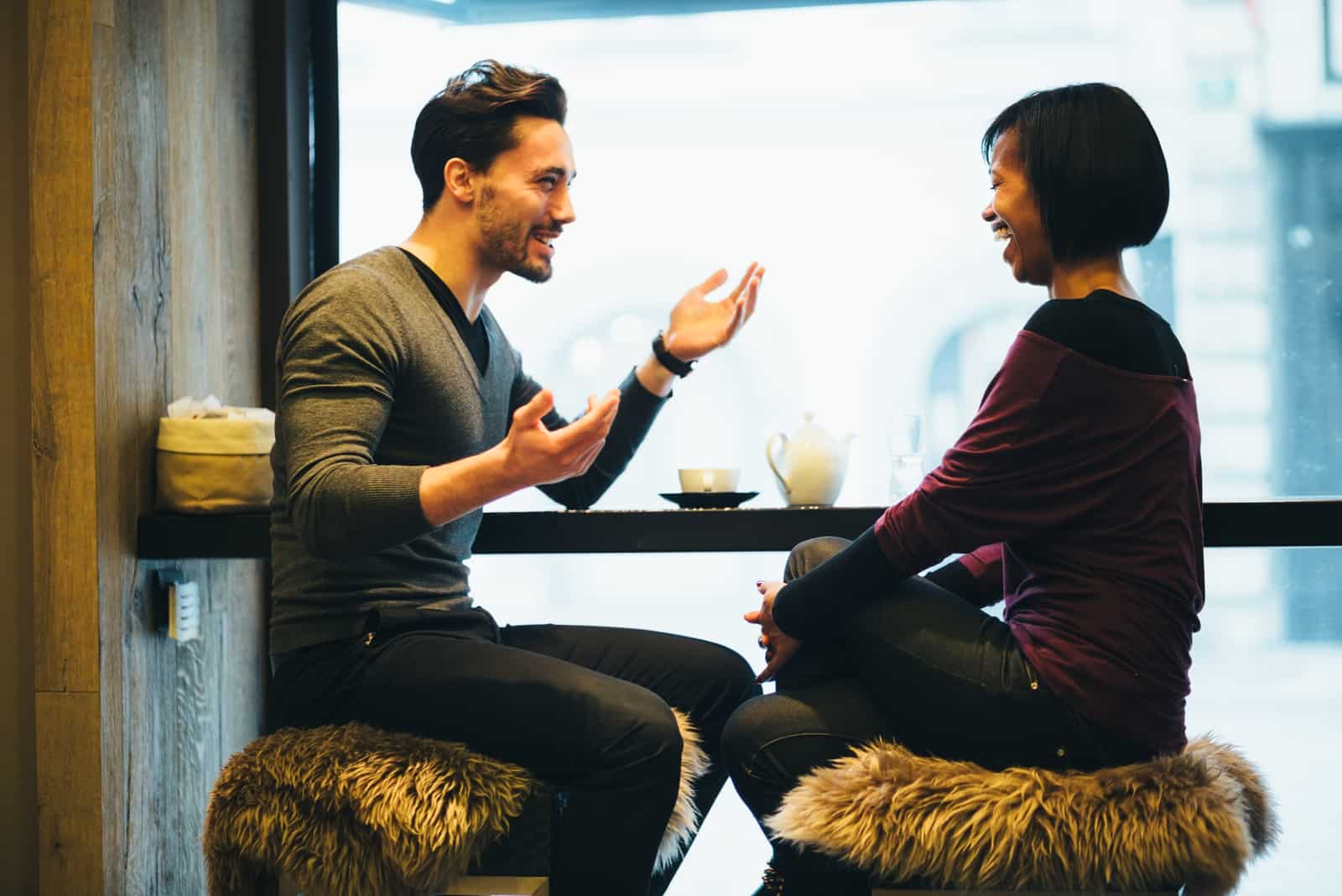 man talking to woman while sitting in cafe