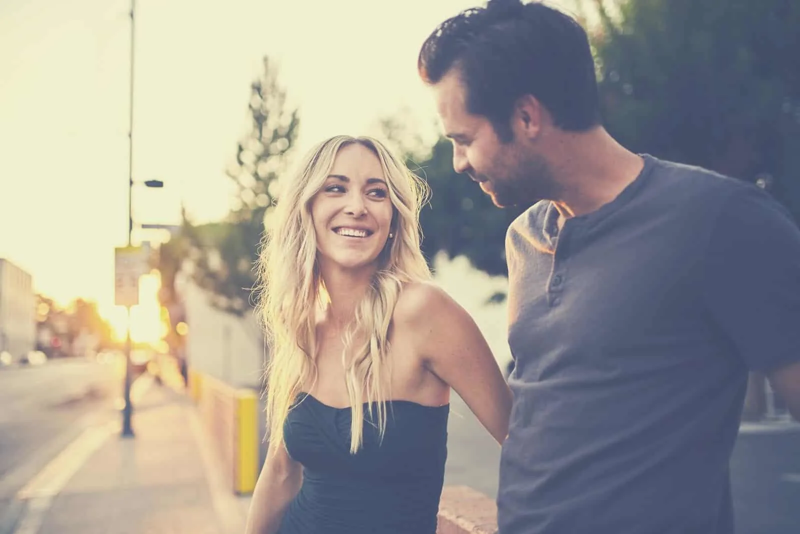 romantic attractive couple looking at each other while standing along the streets