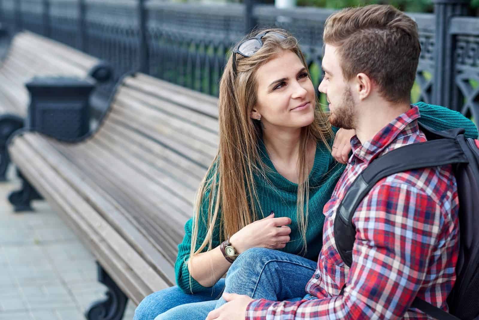 sweet couple hugging and sitting in a bench outdoors