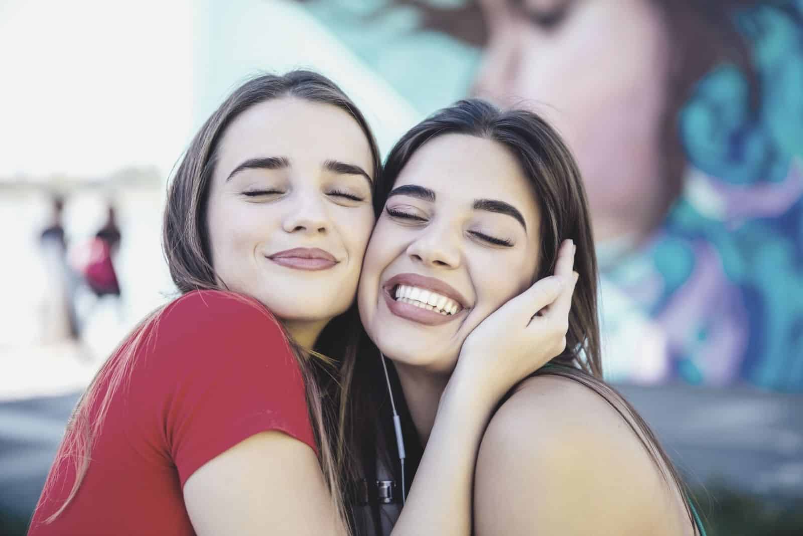 duas melhores amigas a abraçarem-se e a fecharem os olhos numa fotografia de grande plano