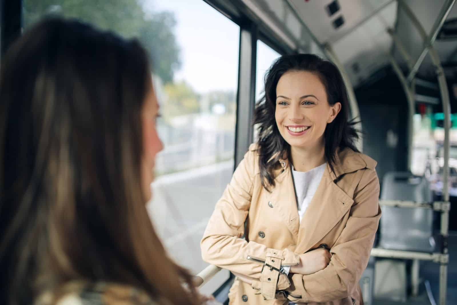 two friends talking standing inside the bus