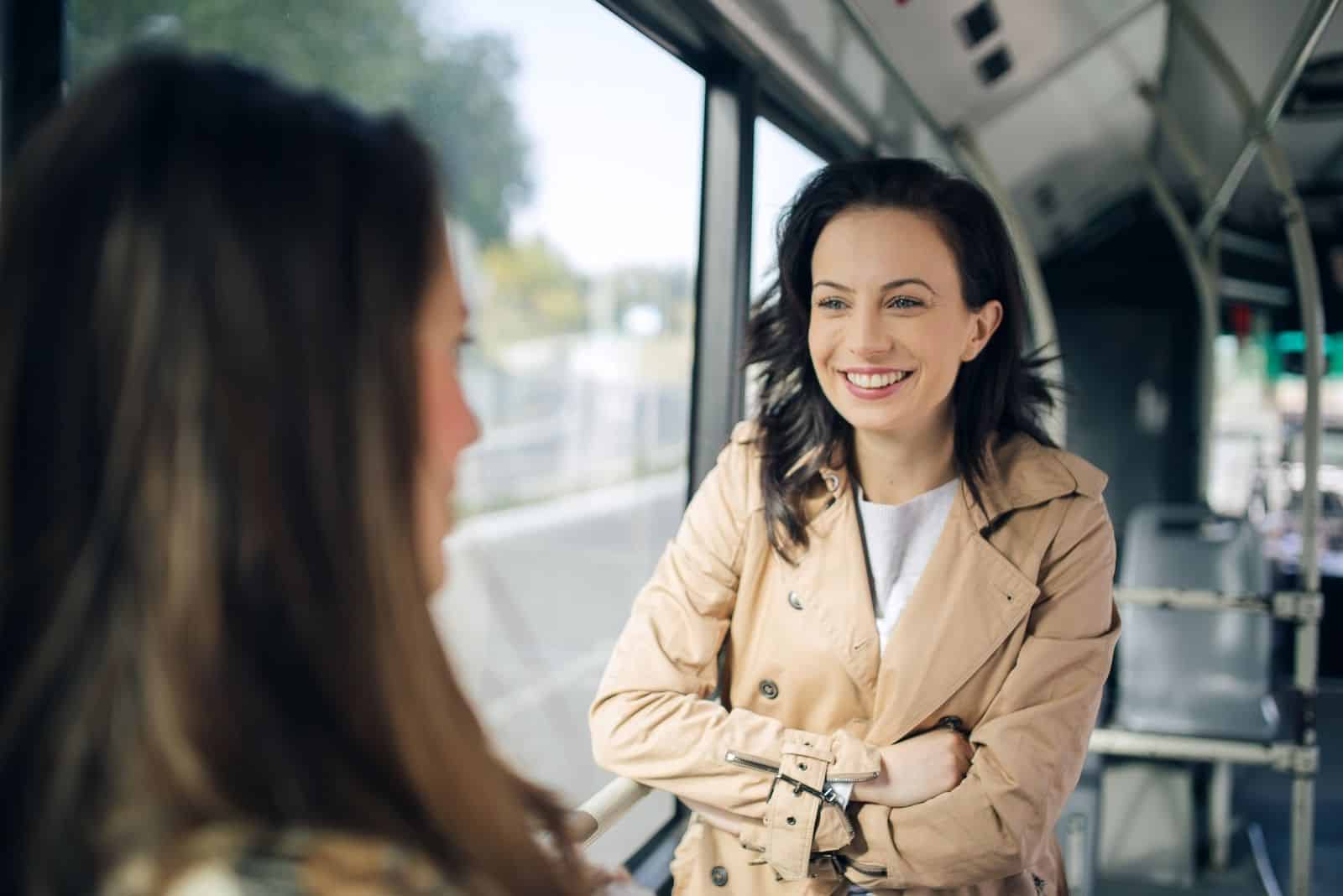 dos amigos hablando de pie dentro del autobús