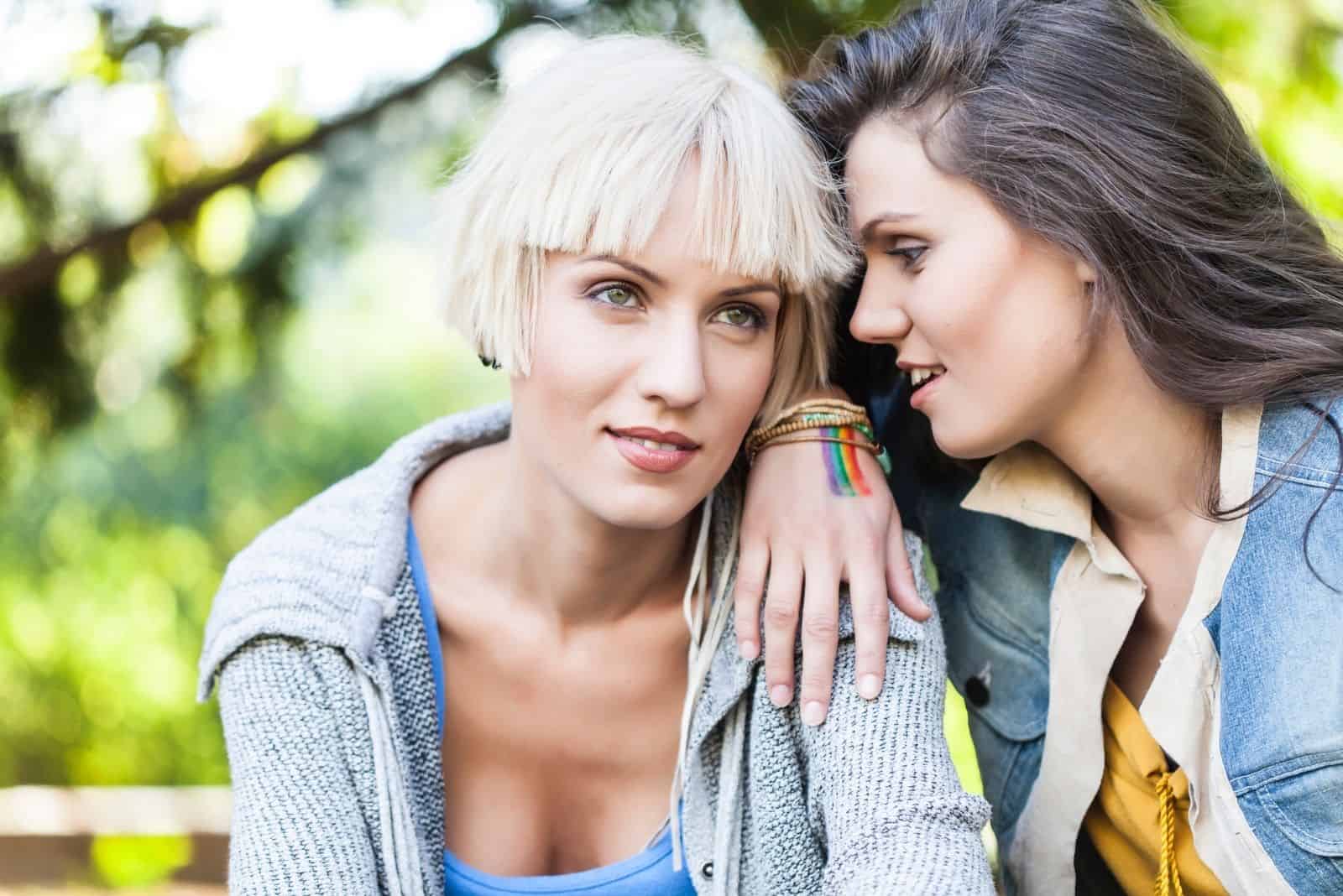 duas amigas divertem-se sentadas no parque a conversar