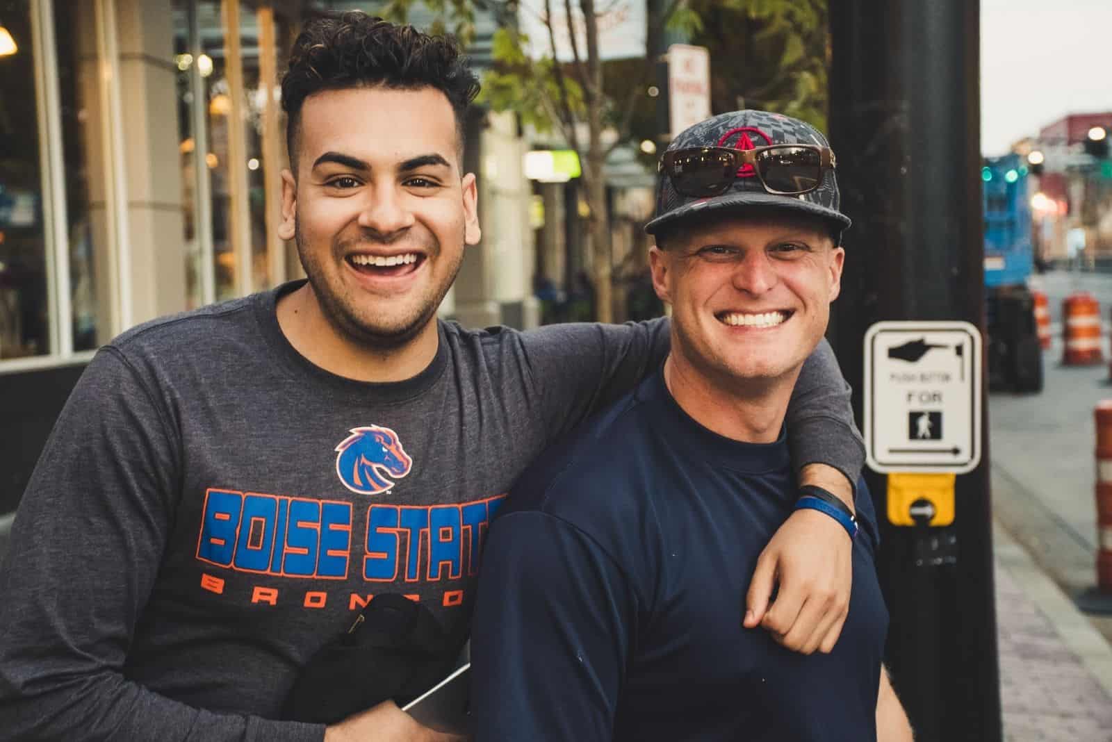 two men standing by the sidewalk looking at the camera smiling