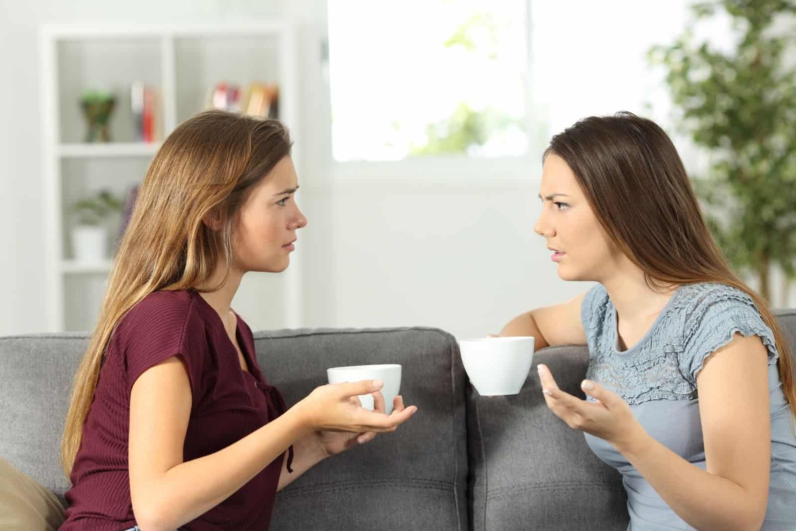 dos amigos serios hablando con una taza de café en el salón