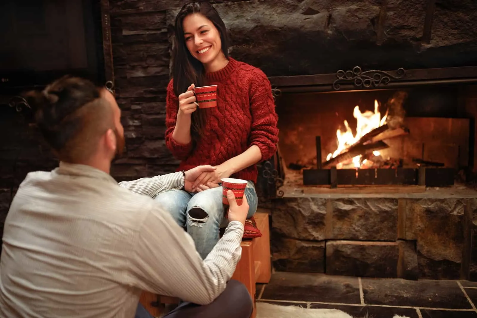 happy woman looking at man while sitting near fireplace