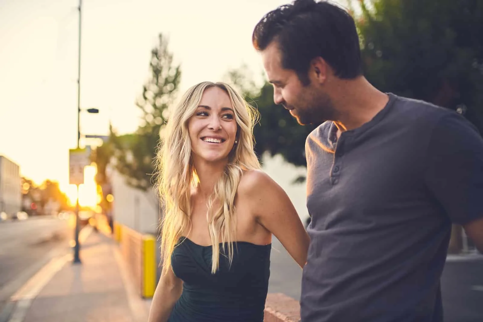 blonde woman smiling while looking at man outdoor