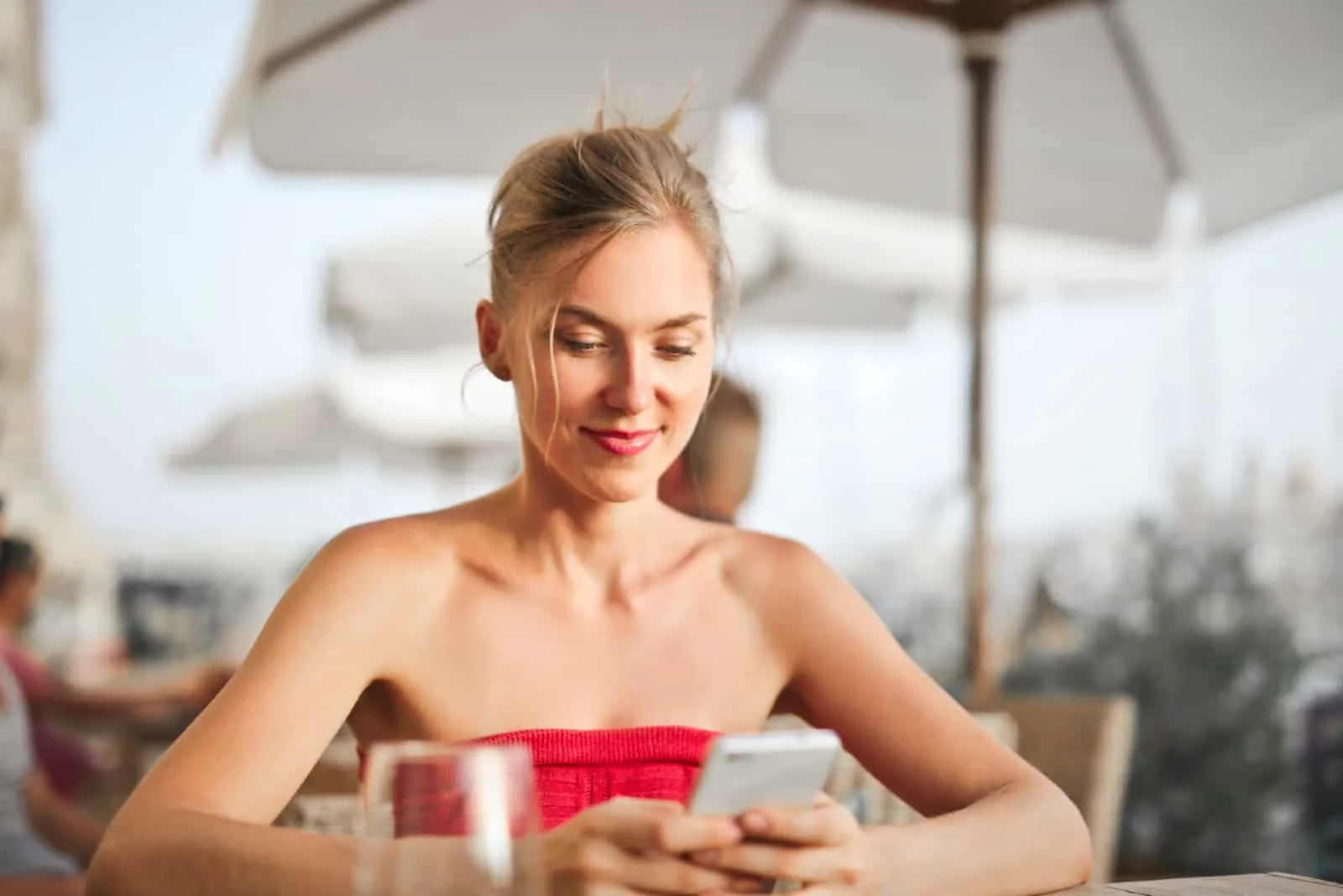 happy woman looking at smartphone while sitting at table