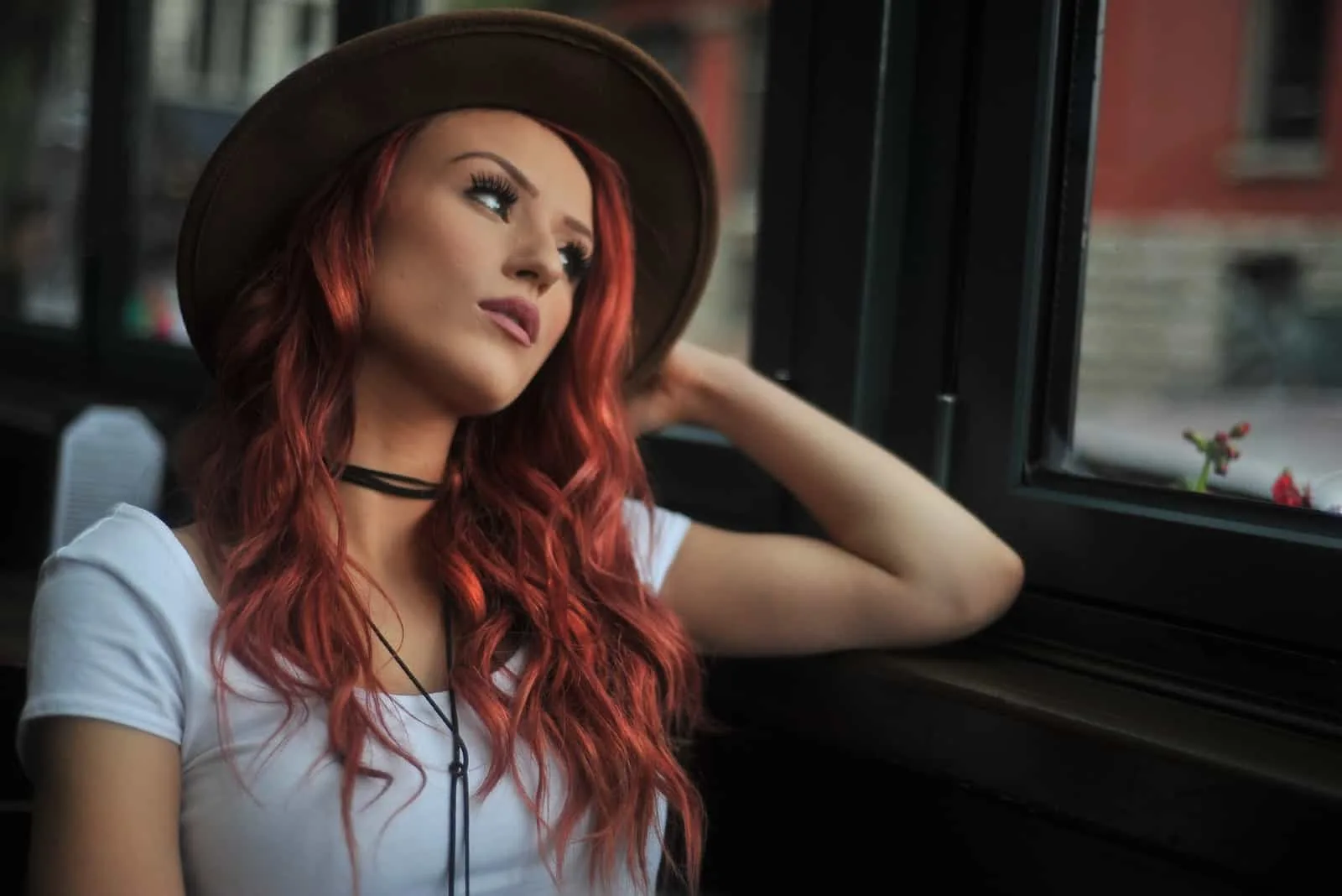 red haired woman with hat looking through window