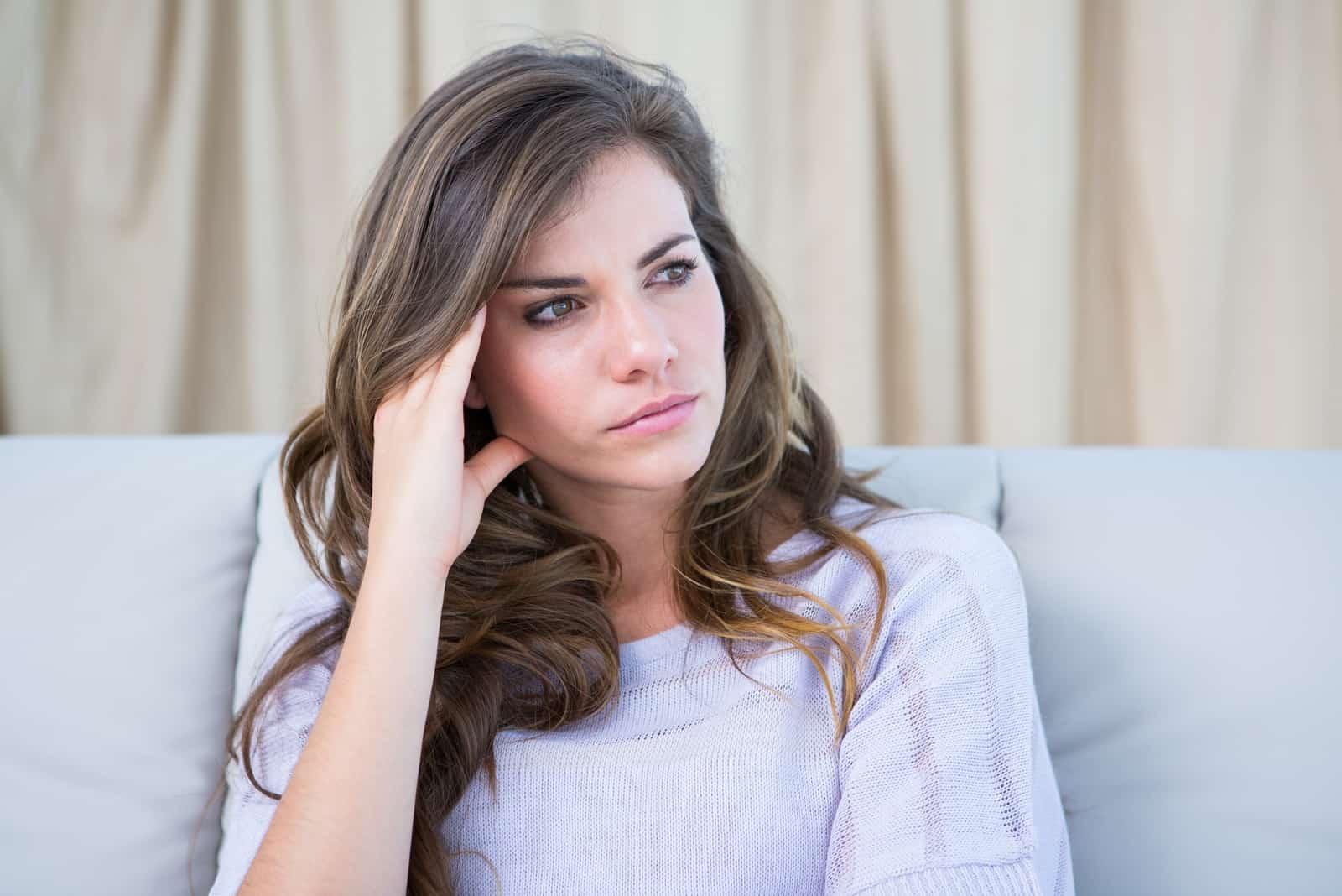 mujer triste sentada en el sofá pensando