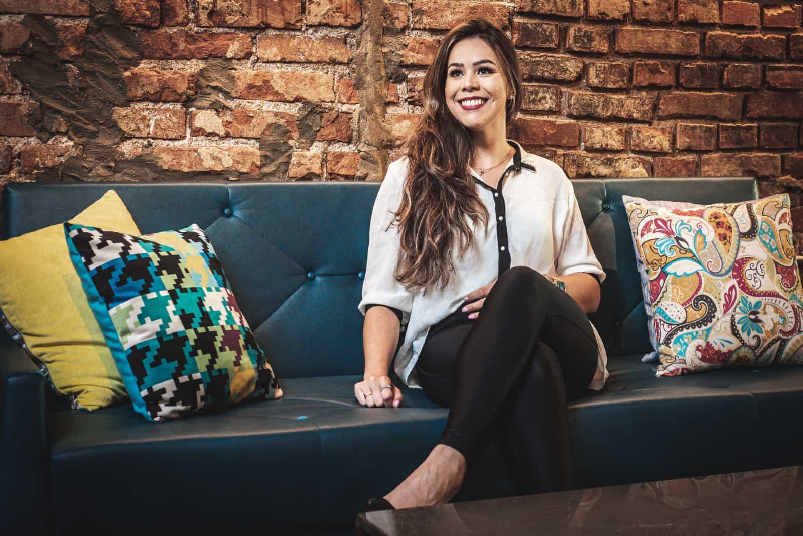 mujer feliz con blusa blanca sentada en un sofá