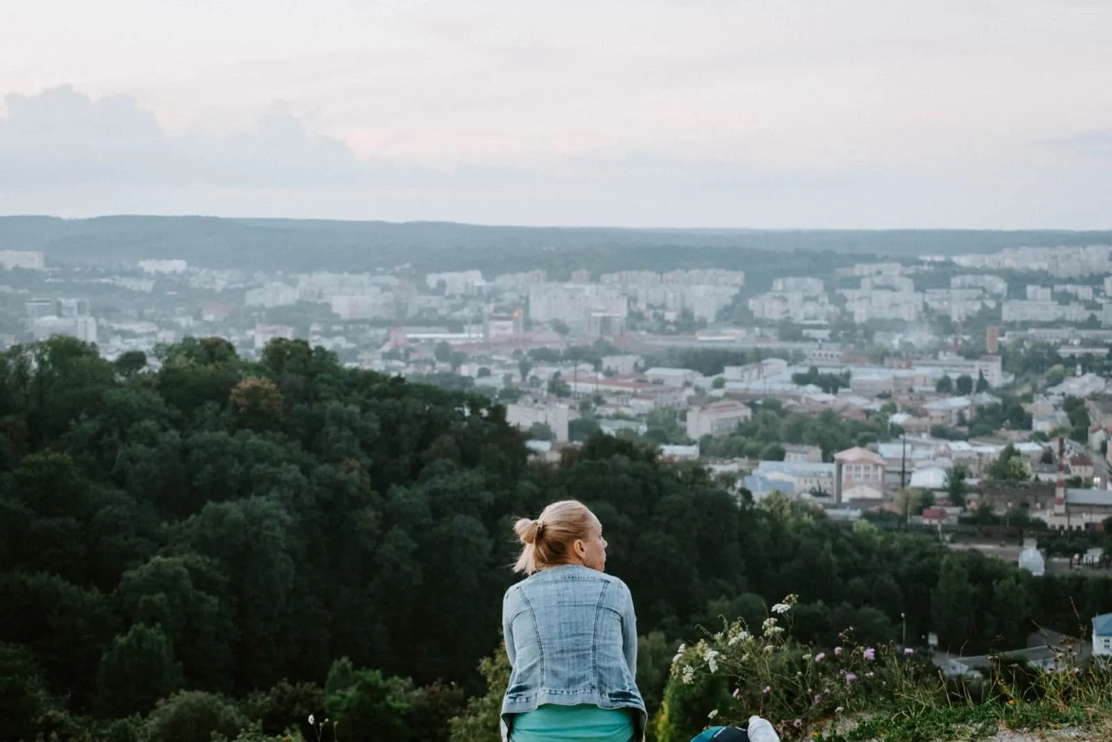blonde woman in denim jacket sitting on top of hill