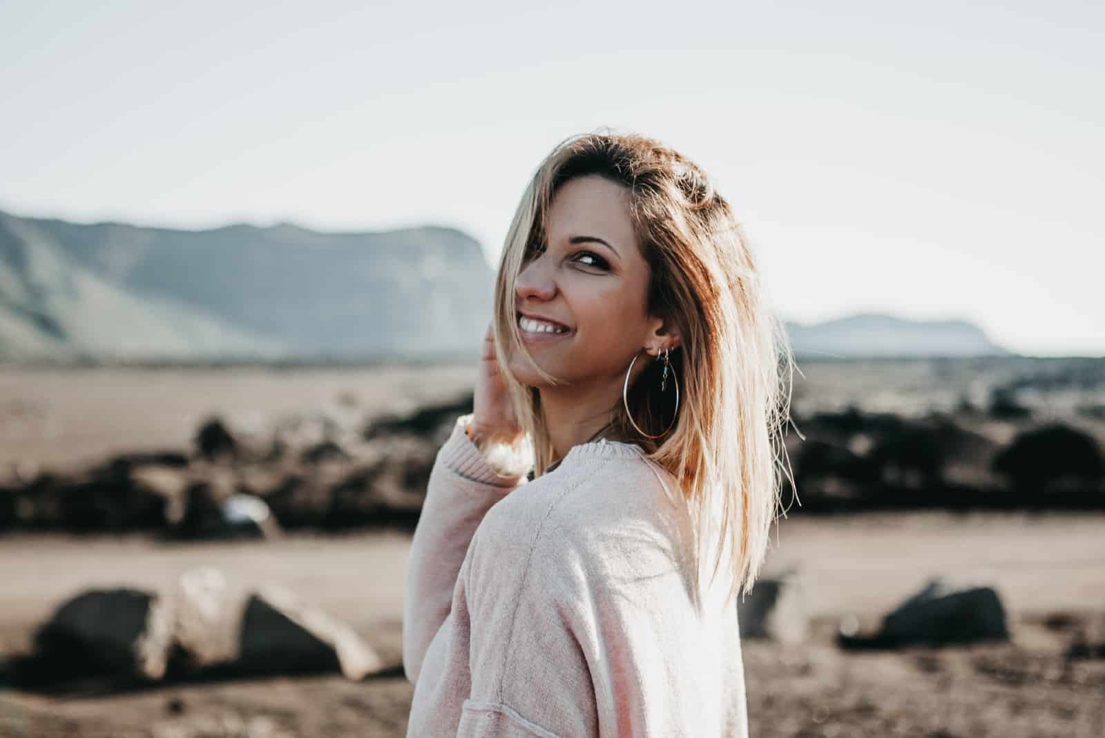 mujer rubia sonriendo de pie en el campo