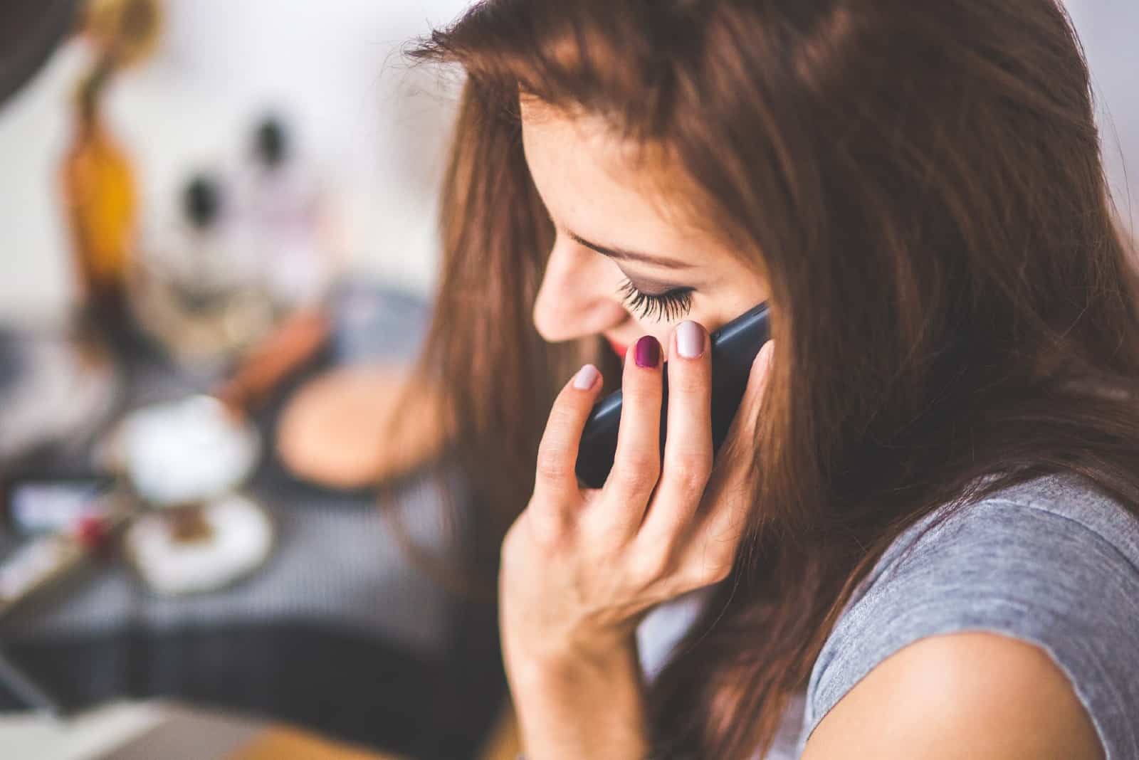 mujer con camiseta gris hablando por teléfono