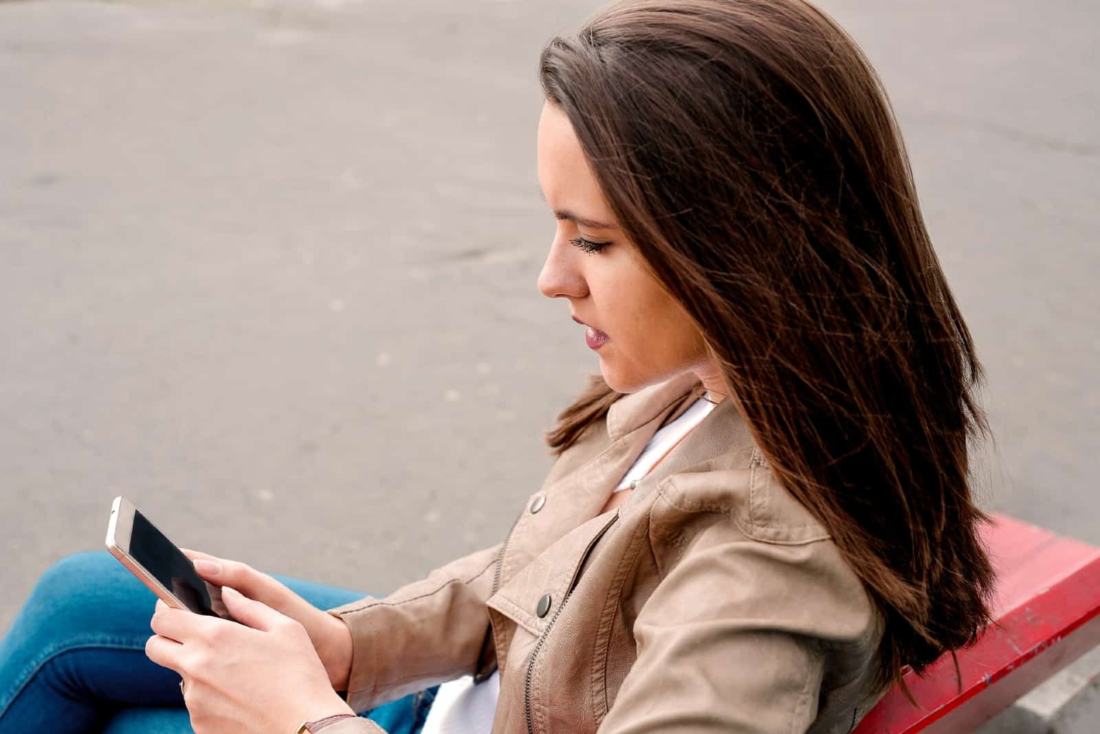woman using smartphone while sitting on bench