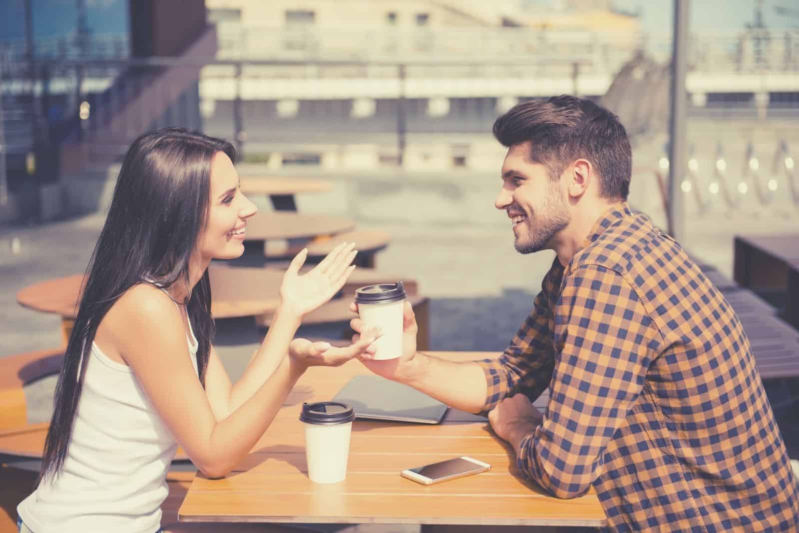 young couple dating in an airy cafe talking and drinking coffee