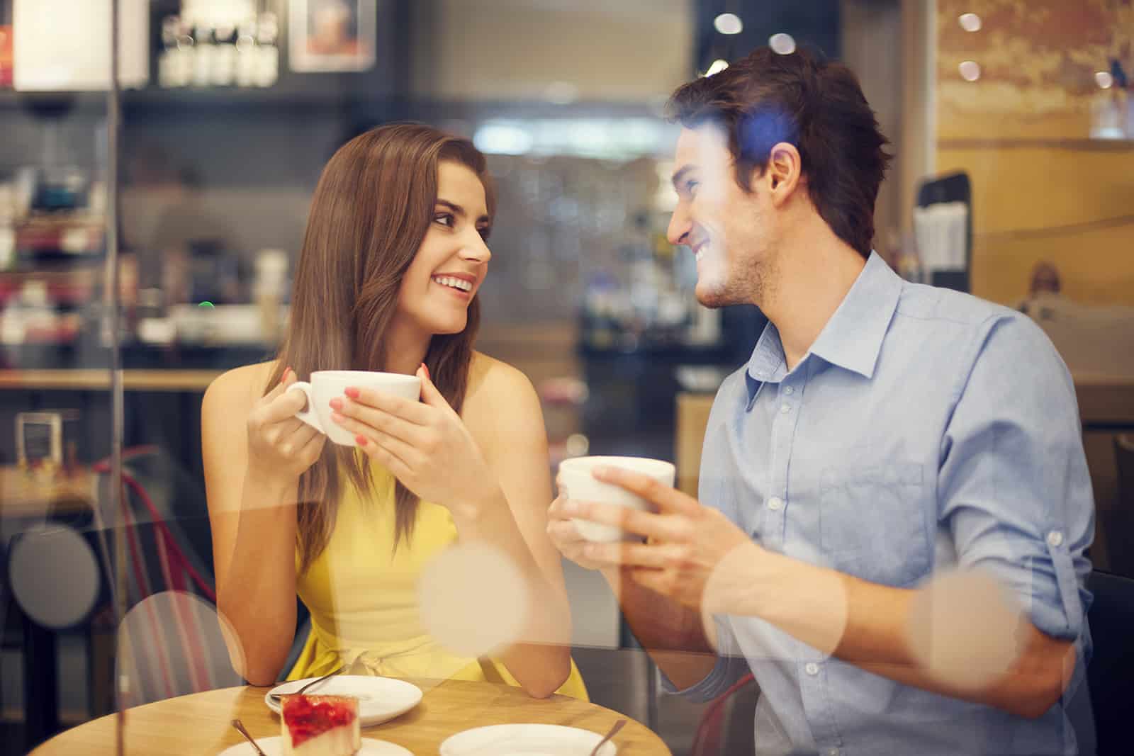 a smiling man and woman talking in a cafe