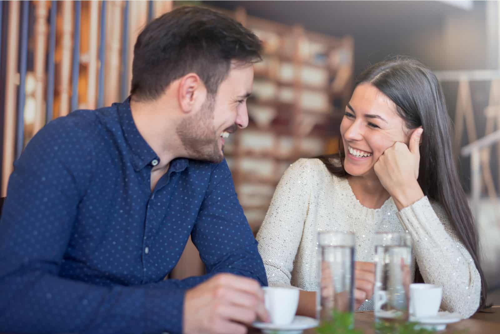 the man and woman sitting at the table smiling and looking into each other's eyes
