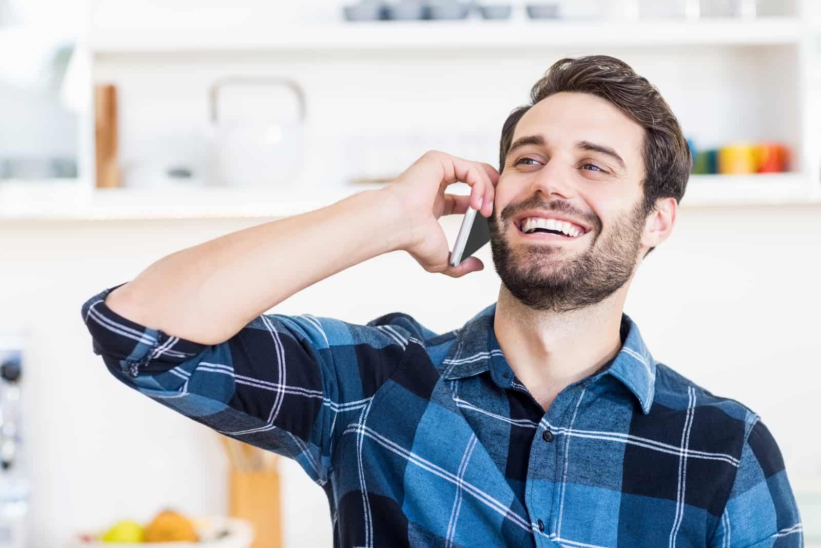 Un hombre habla por teléfono y sonríe en el trabajo