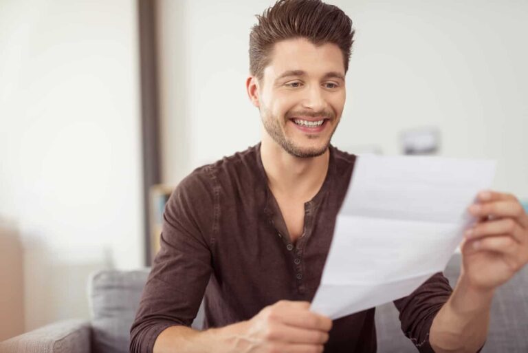 a smiling man reads a letter