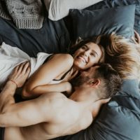 man kissing woman while laying on bed