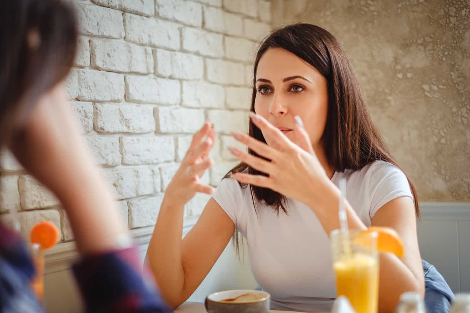 Chica explicando algo con las manos a su amiga en el restaurante