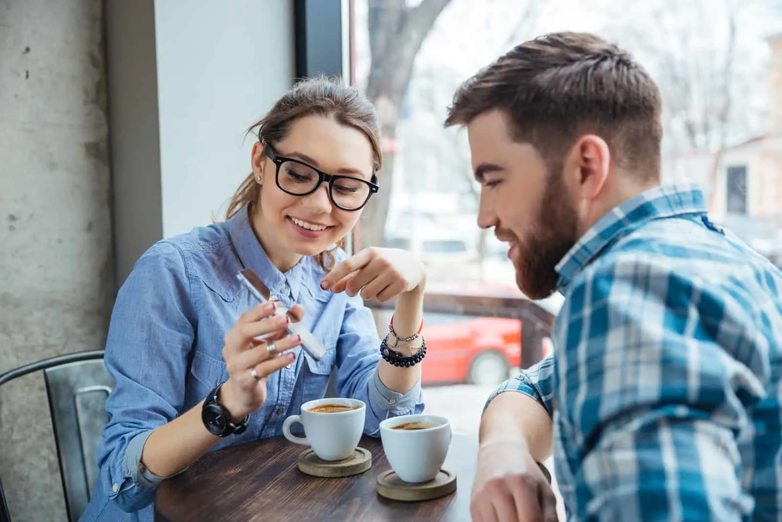 Happy couple using smartphone together and drinking coffee in cafe