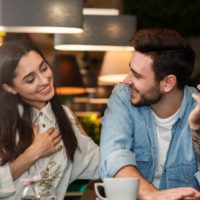 an attractive girl in a cafe flirts with a bearded man